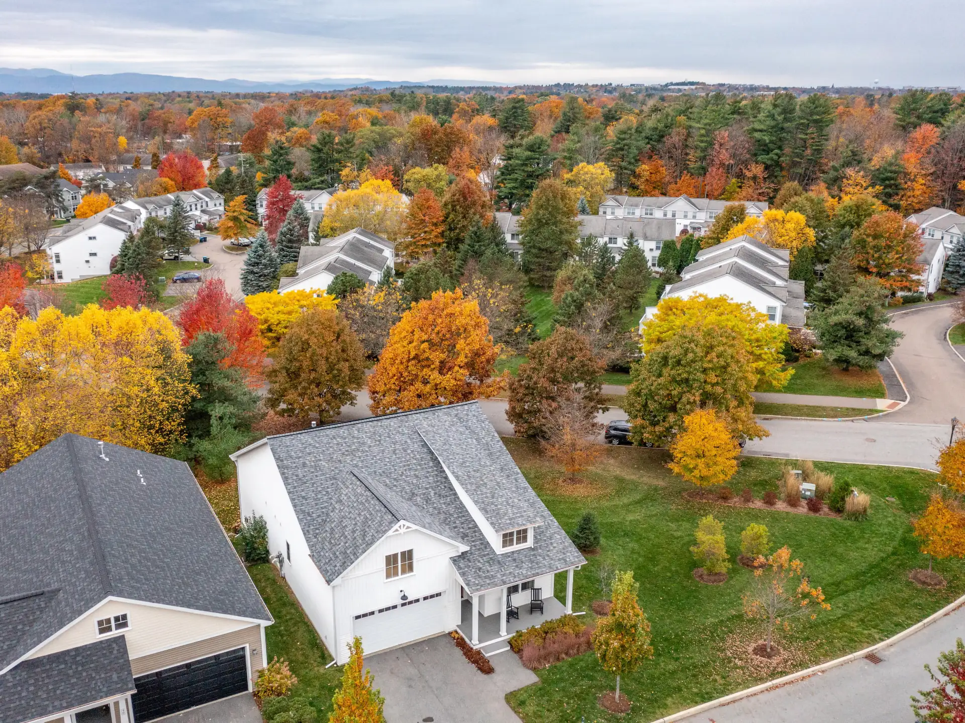 aerial view of neighborhood surrounded by peak fall foliage.
