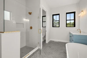 bathroom glass shower with gold fixtures and blue vanity