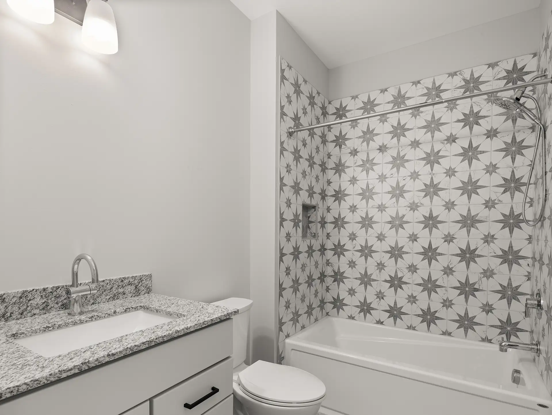 bathroom with star patterned tile tub surround and granite vanity