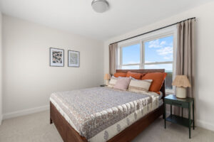bedroom with wood bed frame orange pillows and sky view window