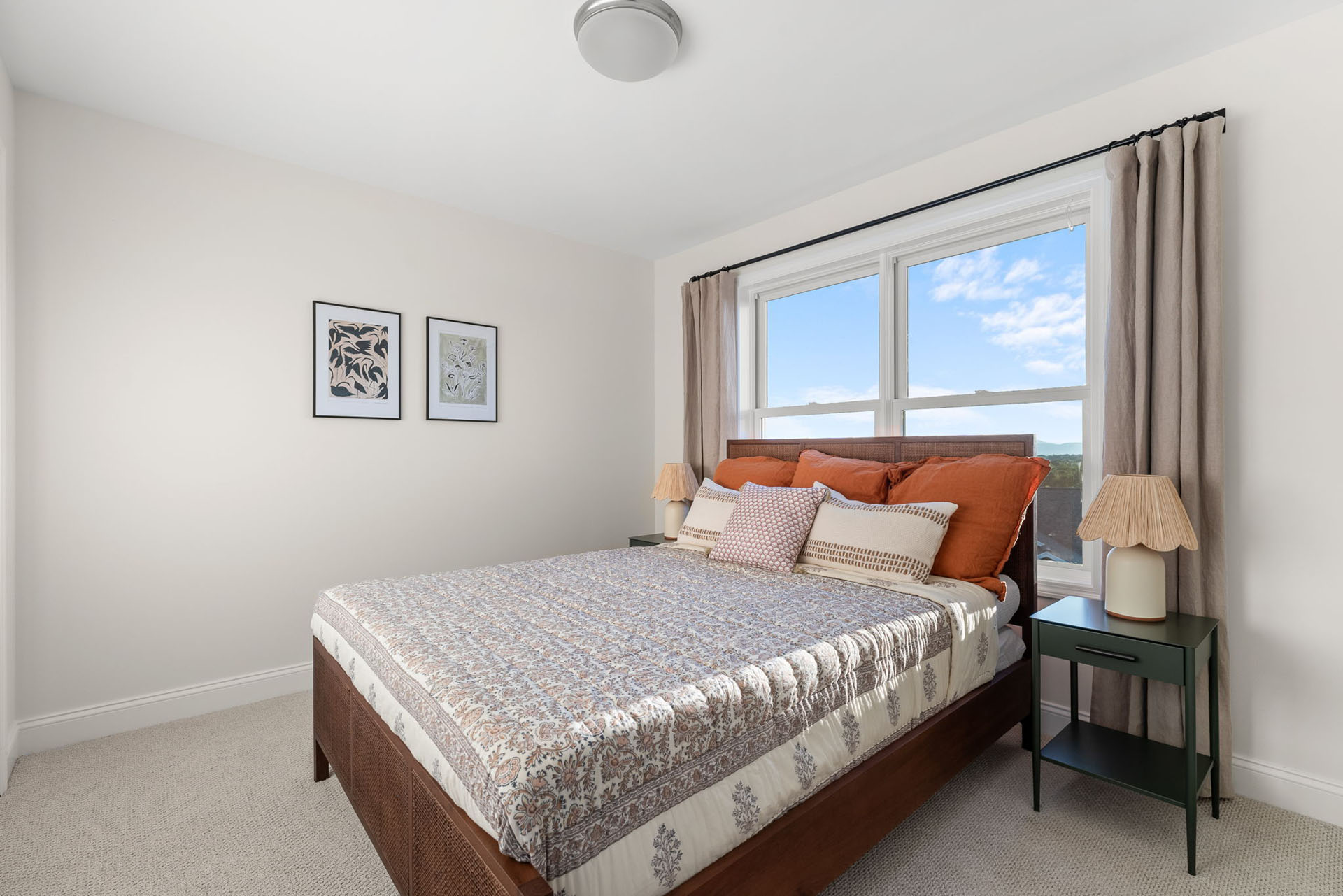 bedroom with wood bed frame orange pillows and sky view window