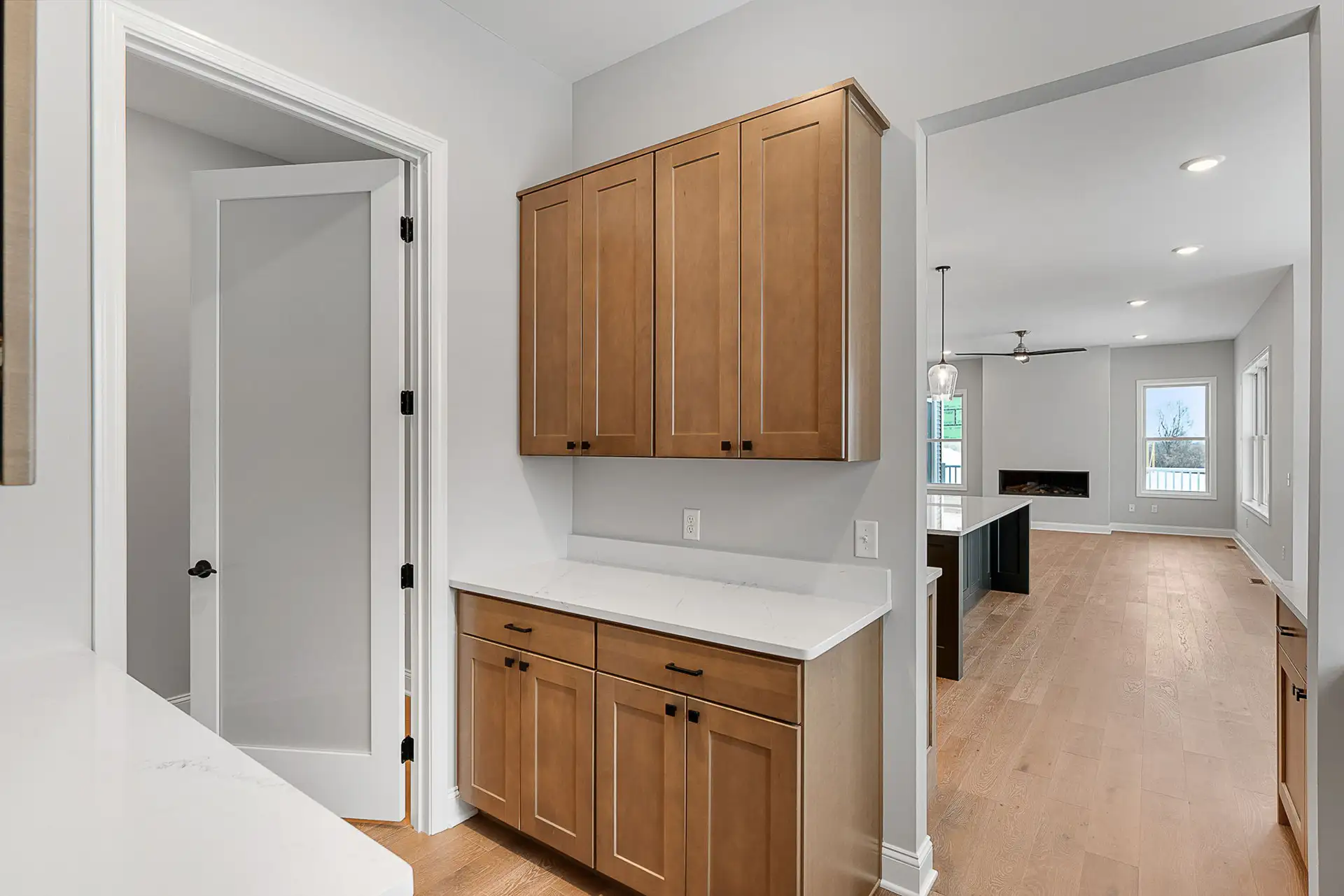 butler pantry wood upper cabinets quartz counter view to living