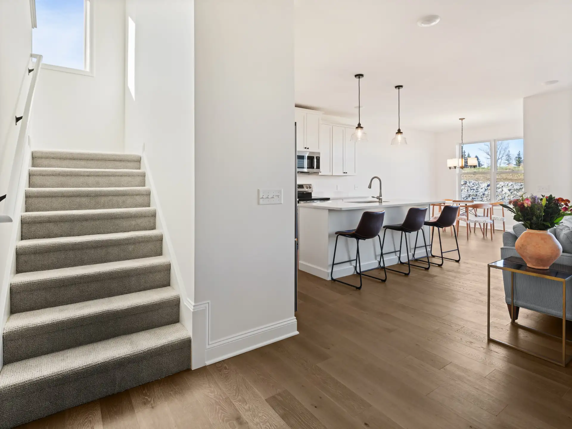 carpeted staircase view to staged kitchen island dining area