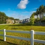 community green with white fence playground and pine trees