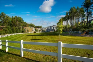 community green with white fence playground and pine trees