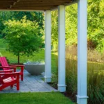 covered patio with red Adirondack chairs and concrete fire bowl