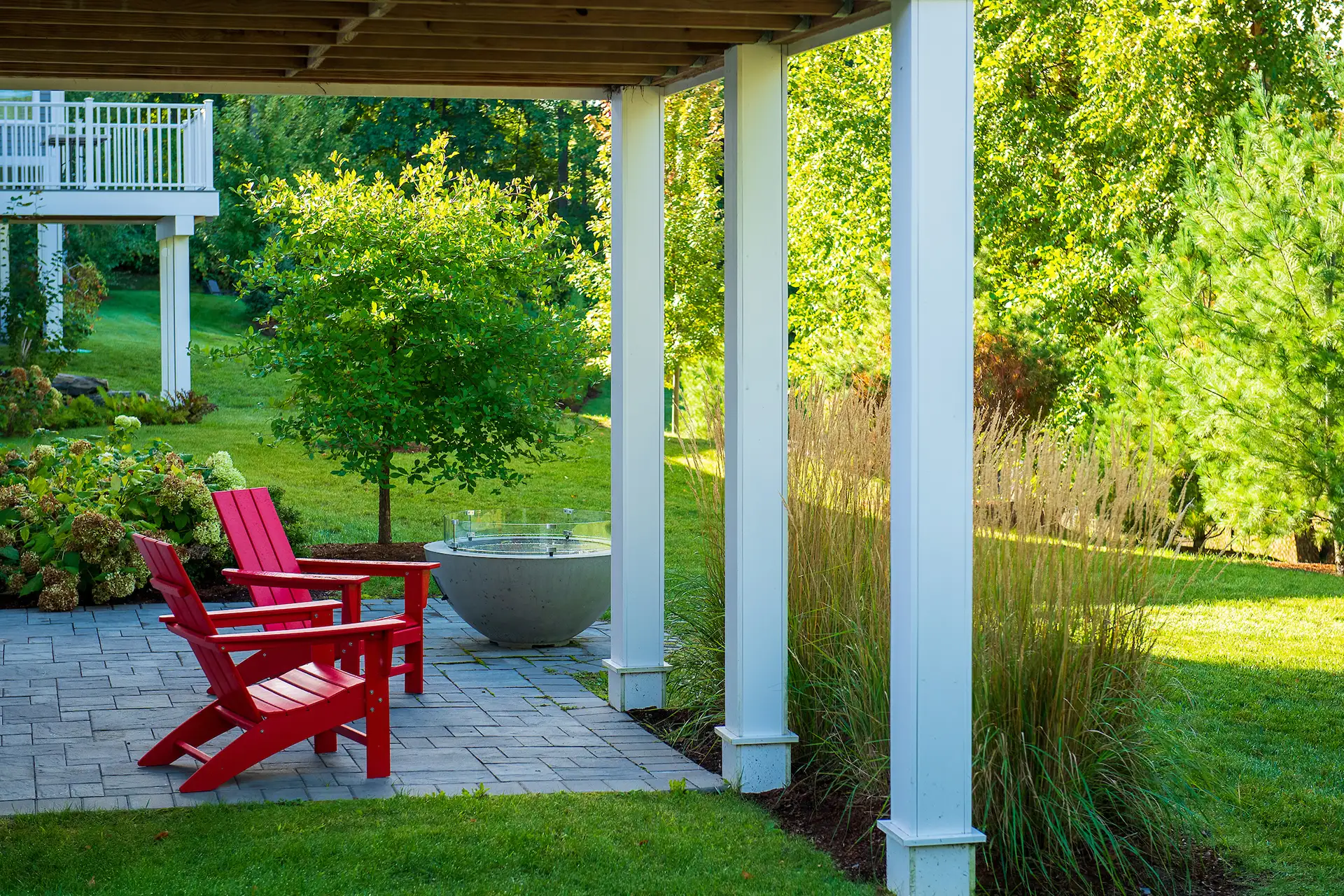 covered patio with red Adirondack chairs and concrete fire bowl