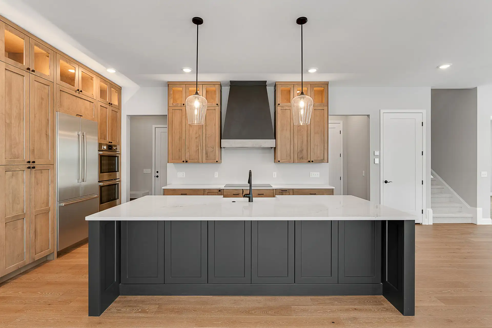 dark island front view wood cabinets black range hood staircase