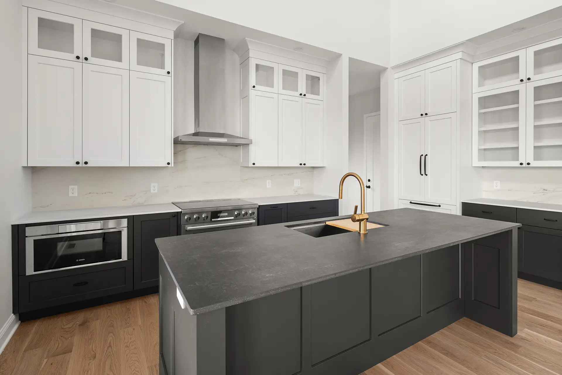 dark island gold faucet white cabinets range hood wide view