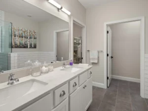double vanity with white cabinets large mirror and walk in closet