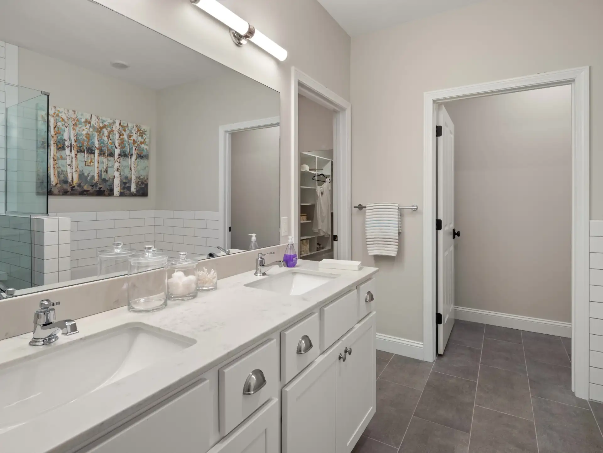 double vanity with white cabinets large mirror and walk in closet