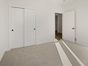 empty bedroom with sliding closet doors and hallway view