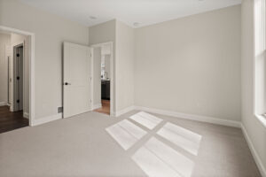 empty beige bedroom with en suite bath and walk in closet doors