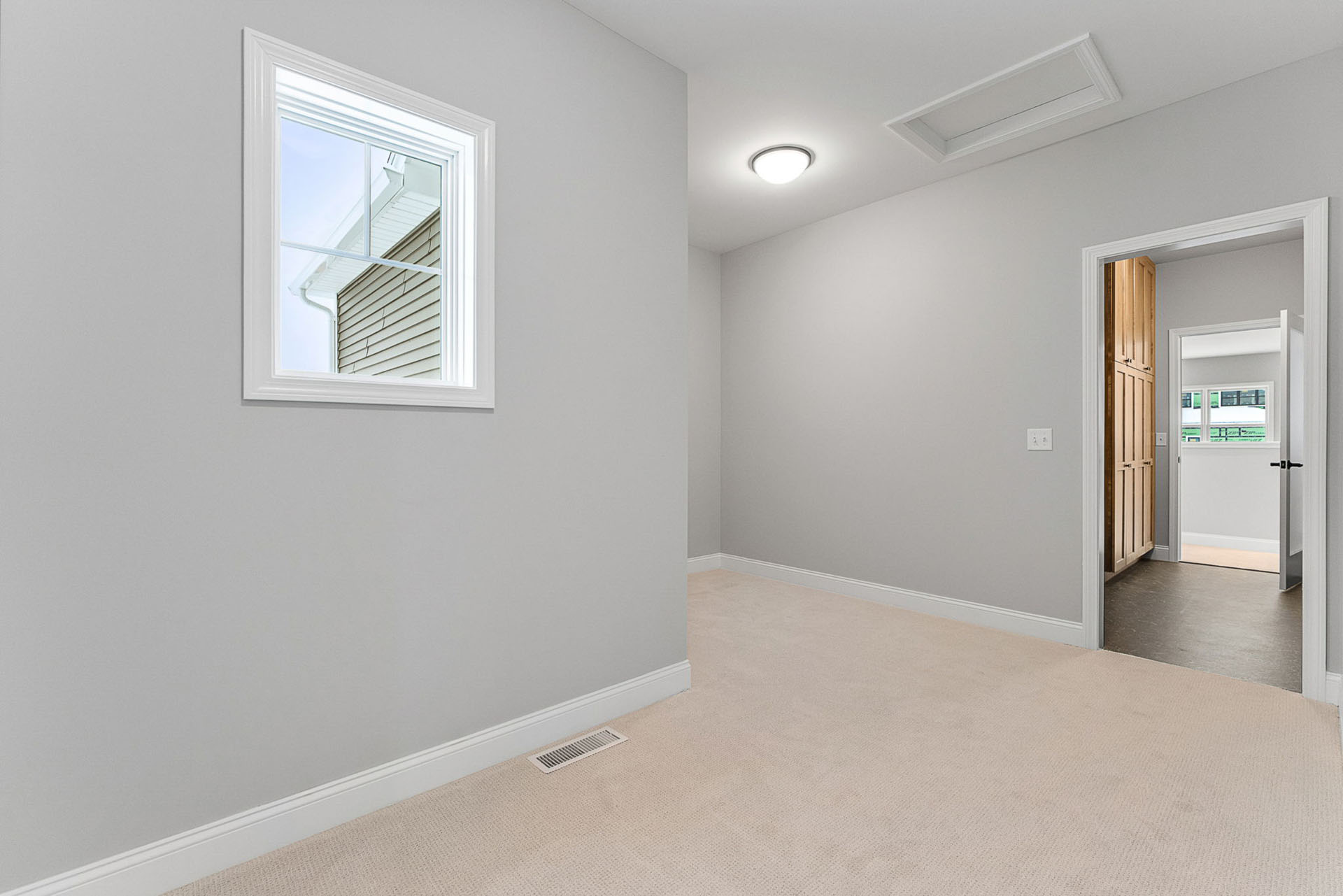 empty gray bedroom with attic hatch and view to wood closet