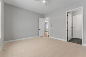 empty gray bedroom with ceiling fan and en suite bath door