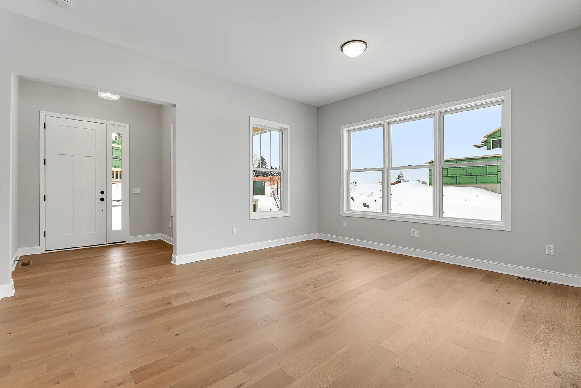 empty open plan living area with front door and winter view windows