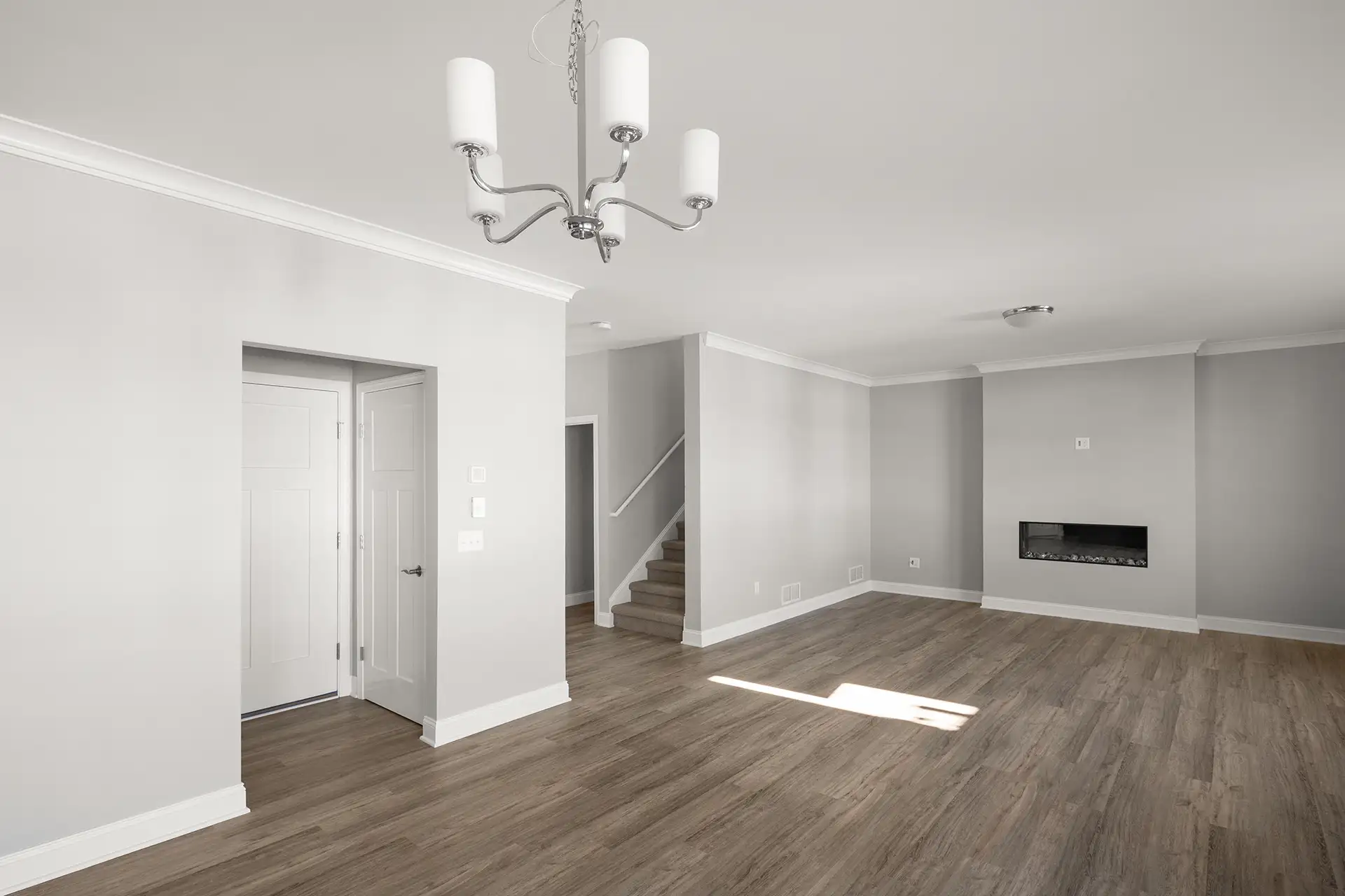 empty open plan living room with crown molding chandelier and staircase