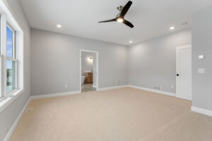 empty primary bedroom with black ceiling fan and en suite doorway