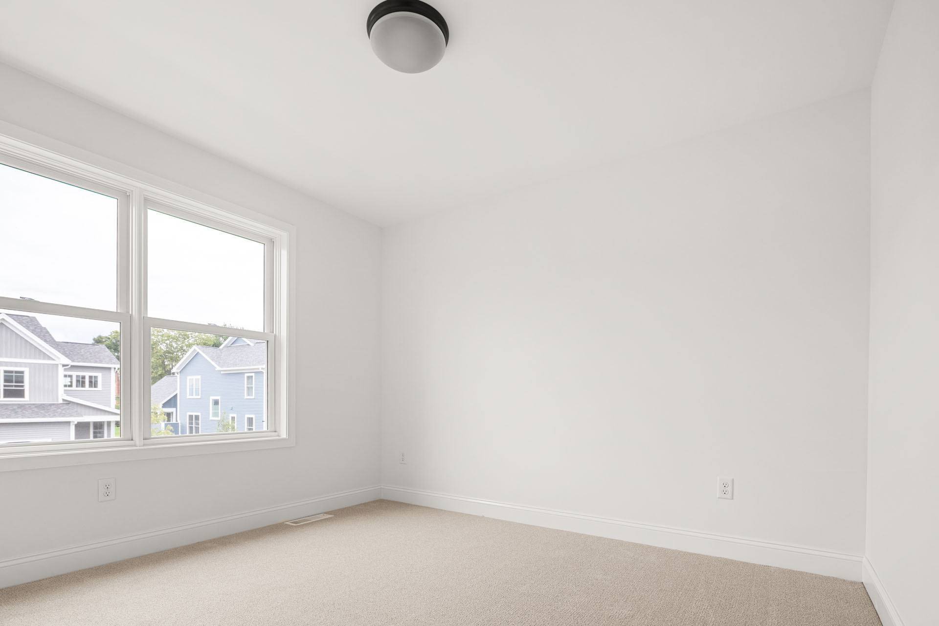 empty white bedroom with corner window and blue house street view