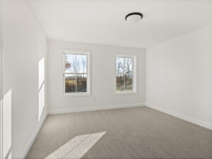empty white bedroom with two narrow windows and autumn yard view
