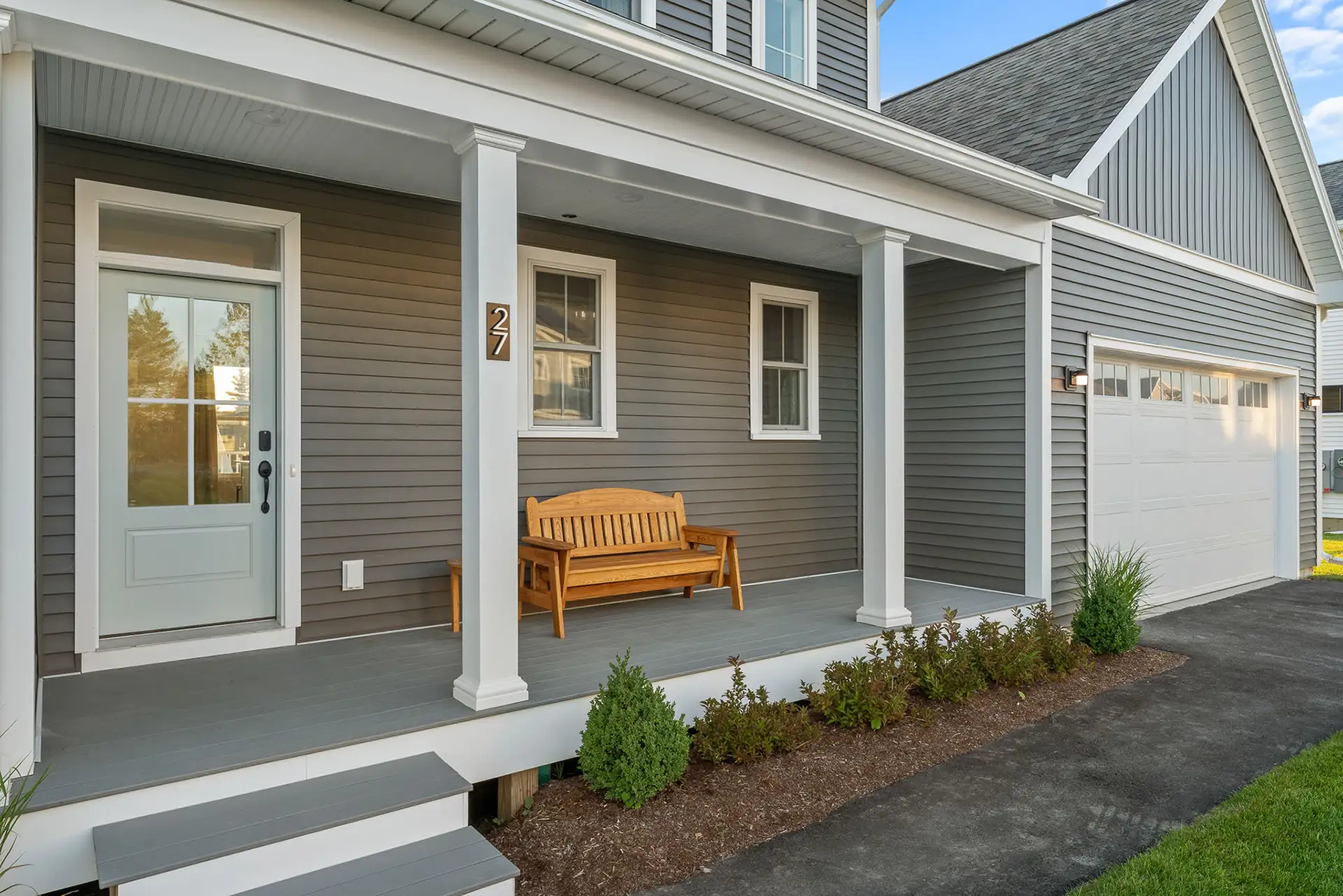 front porch with wood bench and garage side angle view