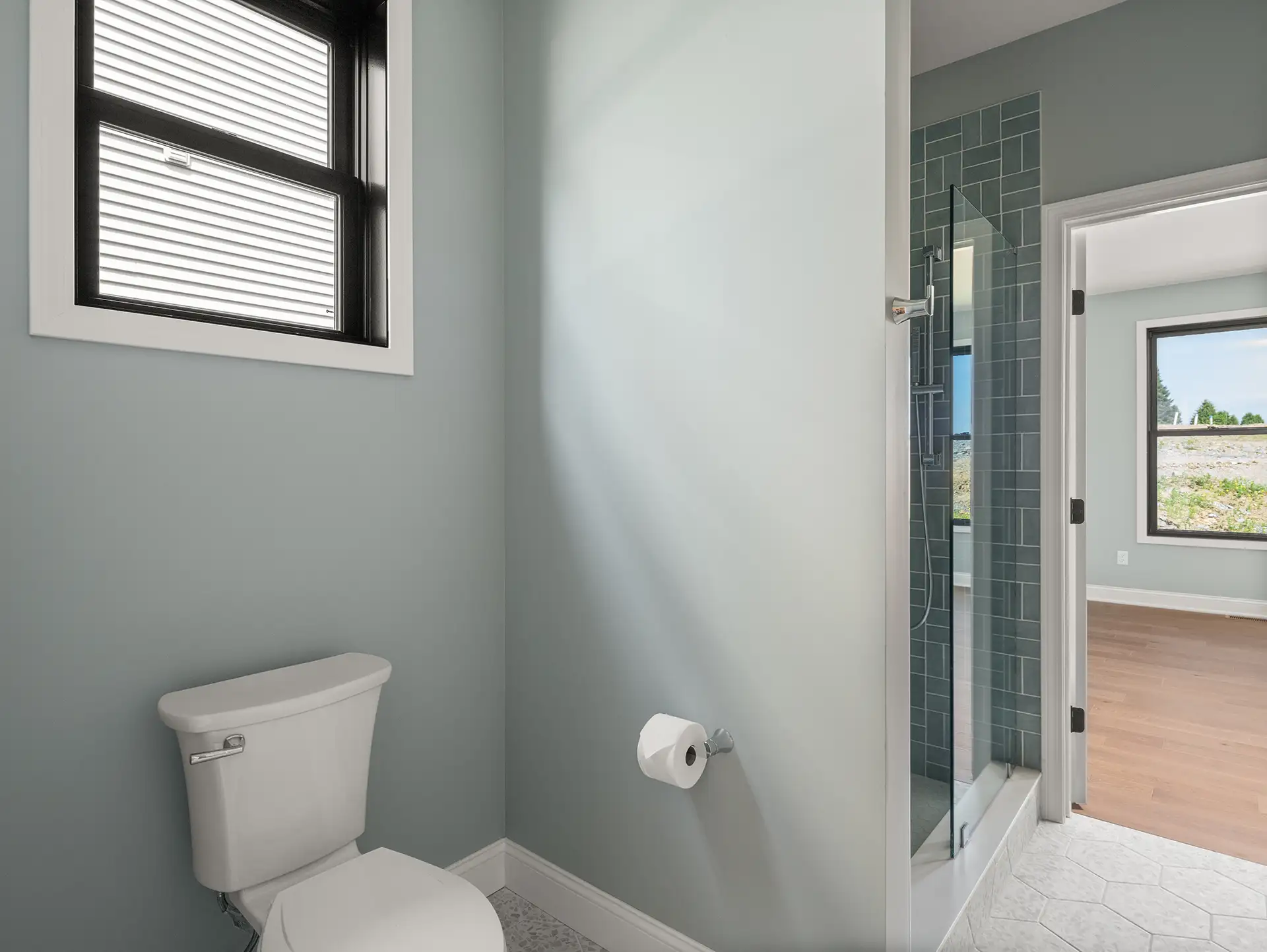 gray bathroom with toilet glass shower and bedroom view