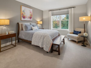 gray bedroom with sleigh bed colorful wall art and sitting chair.