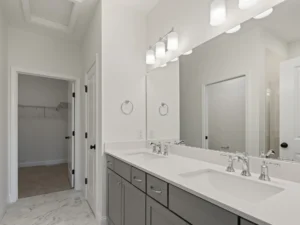 gray double vanity with marble floor and walk in closet door