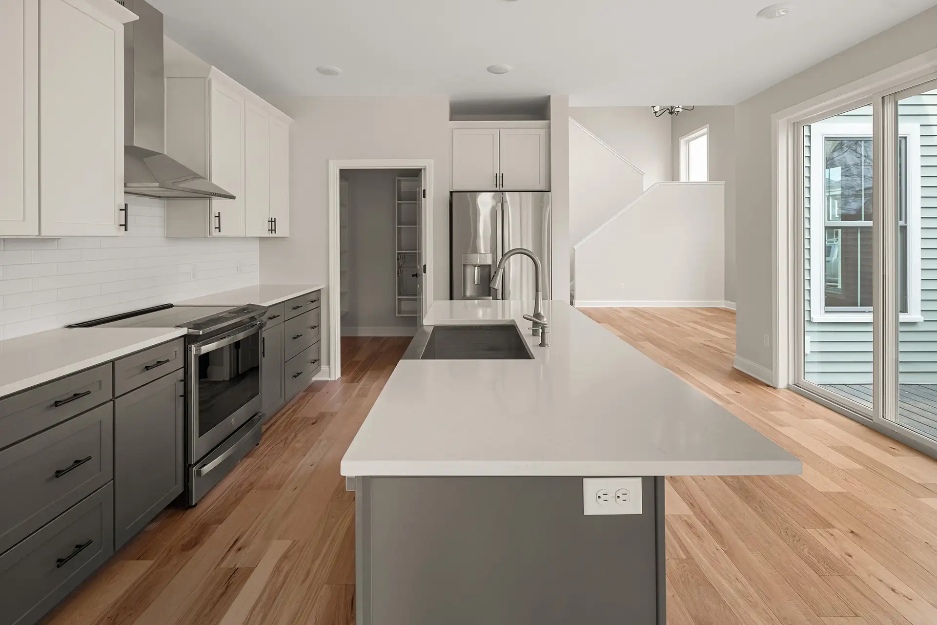 gray island white upper cabinets subway tile pantry sliding door