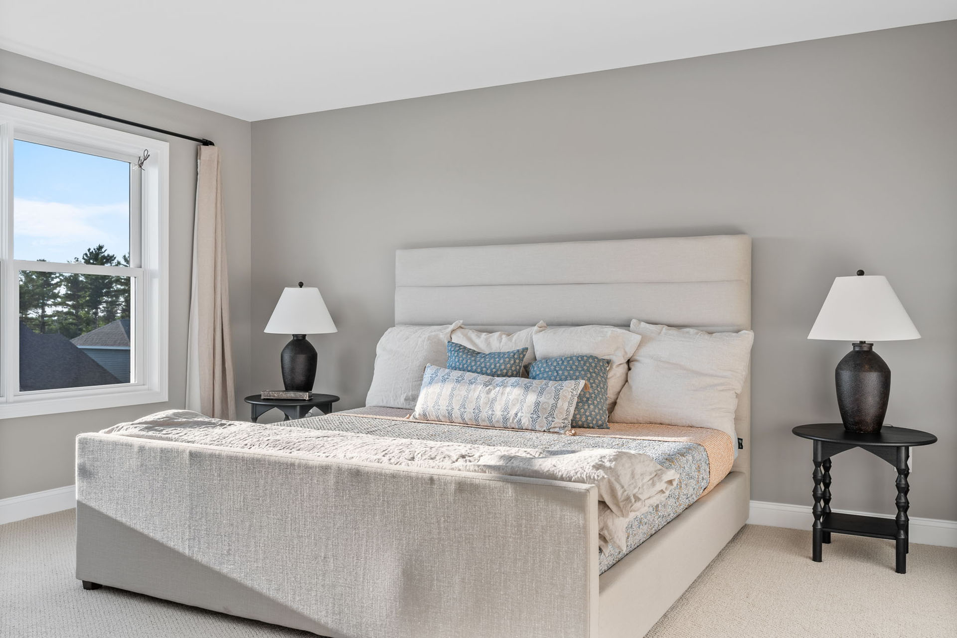 gray primary bedroom with upholstered bed and black nightstands
