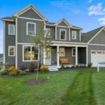 gray siding model home exterior with covered porch and garage