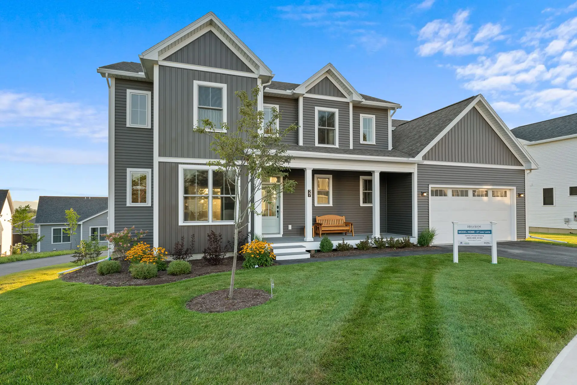 gray siding model home exterior with covered porch and garage