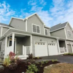 gray siding townhome exterior with covered porch and two car garage