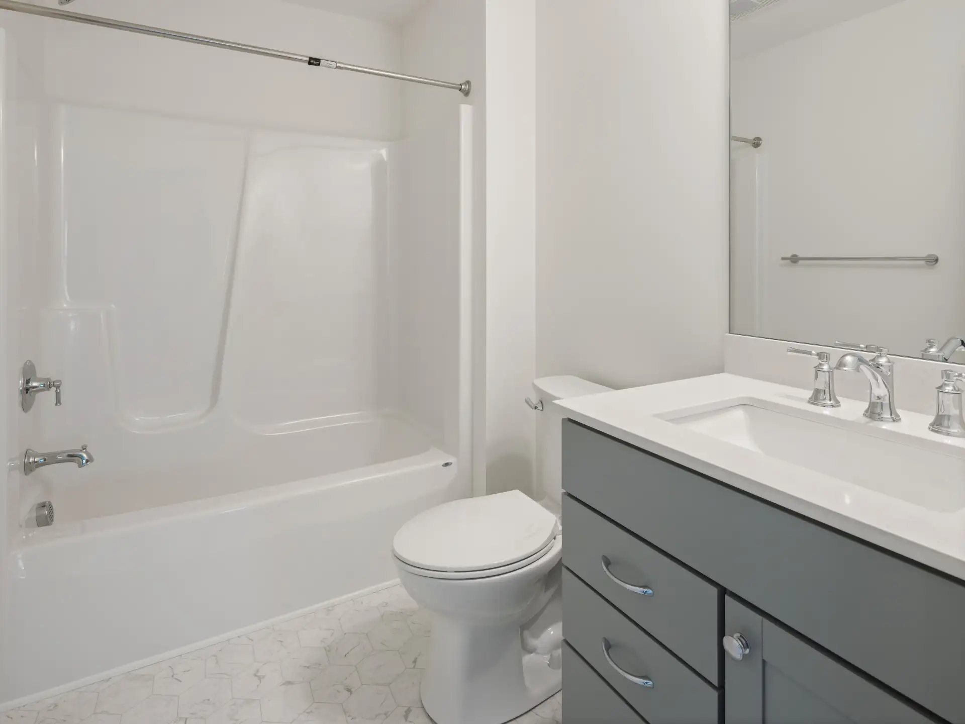 gray vanity with tub shower unit and mosaic floor tile
