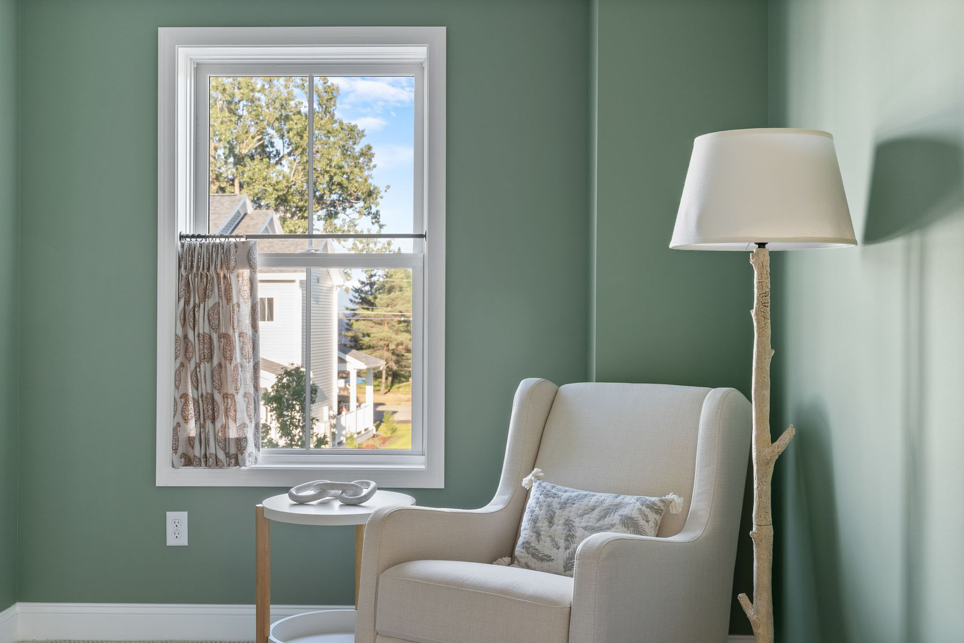 green nursery reading nook with armchair and tree branch lamp