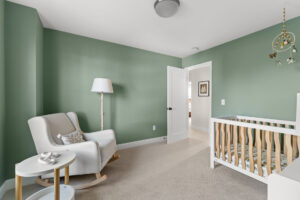 green nursery rocker corner with floor lamp and crib mobile