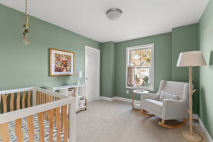 green nursery wide view with crib rocker and deer wall art