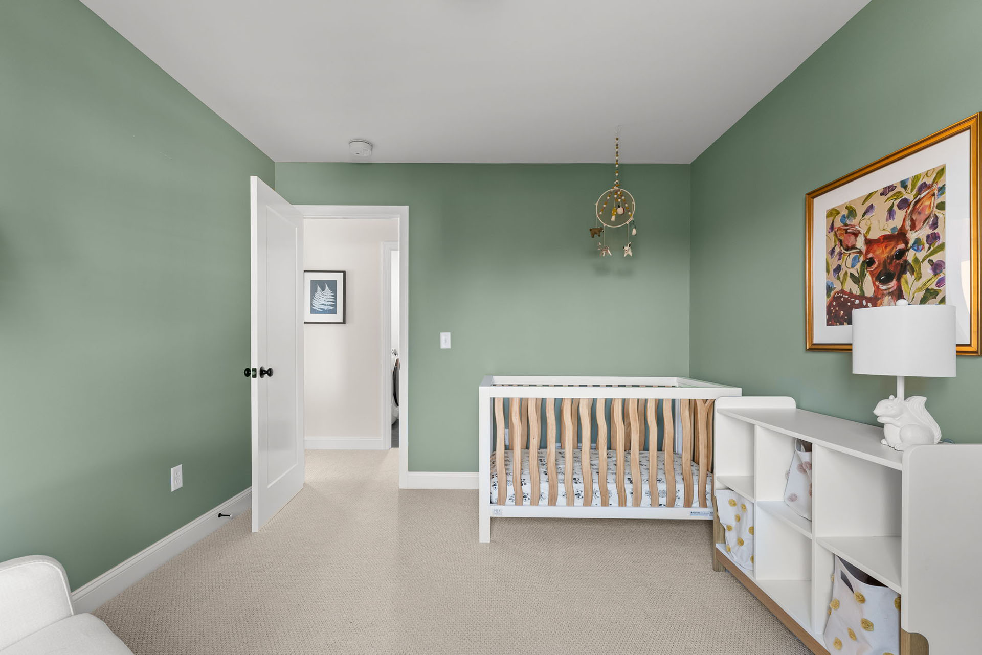 green nursery with crib dream catcher mobile and cubby dresser