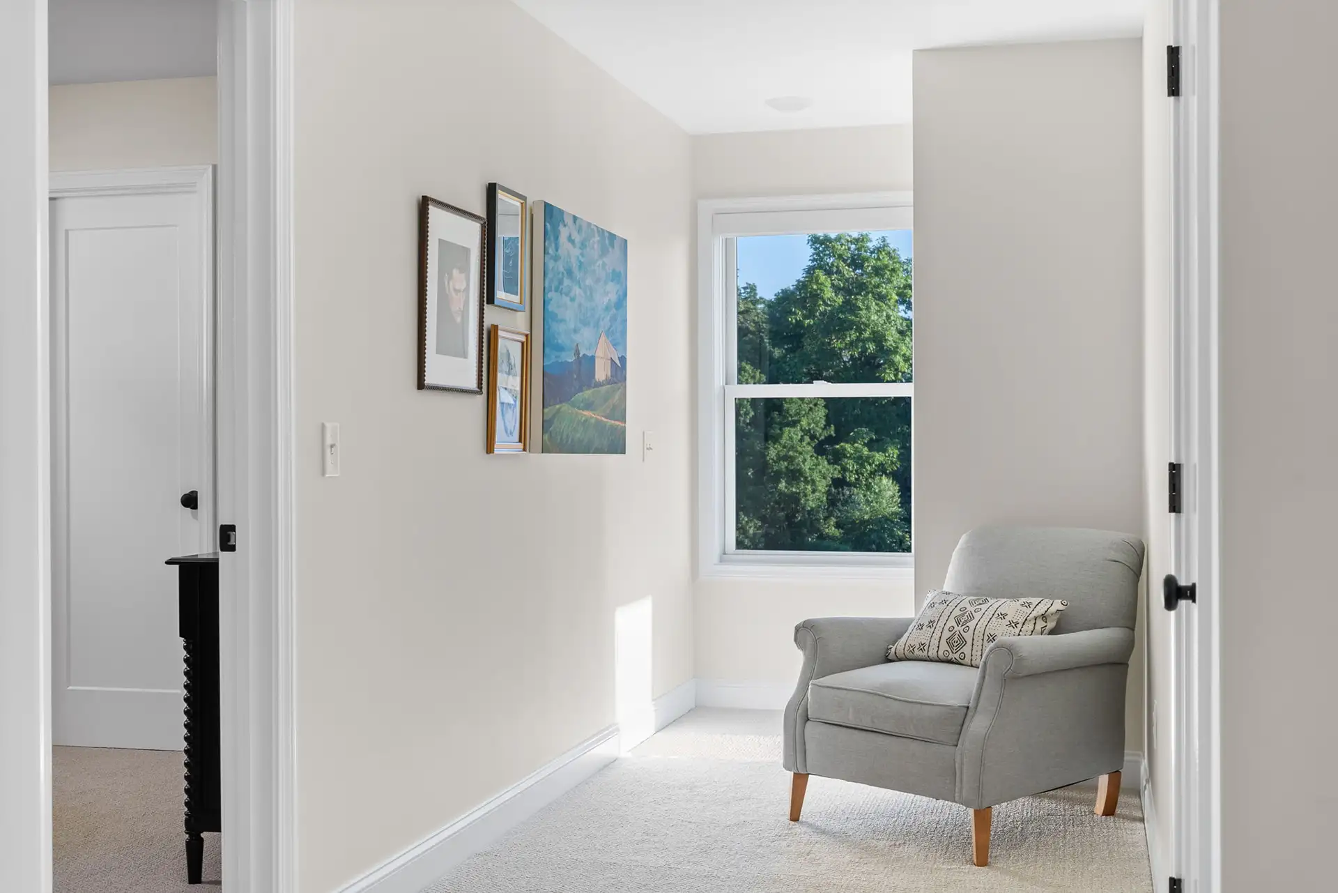 hallway sitting nook gray armchair gallery wall tree window