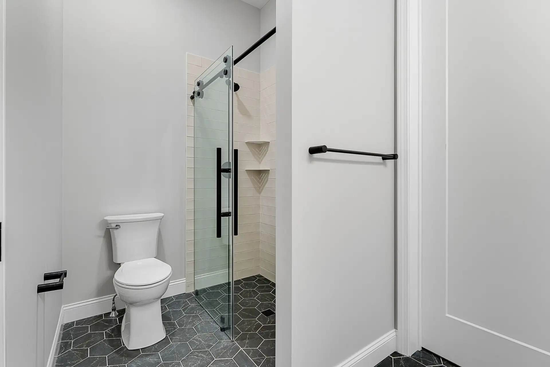 hex tile bathroom sliding glass shower toilet view