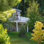 home rear with upper deck and landscaped yard through trees