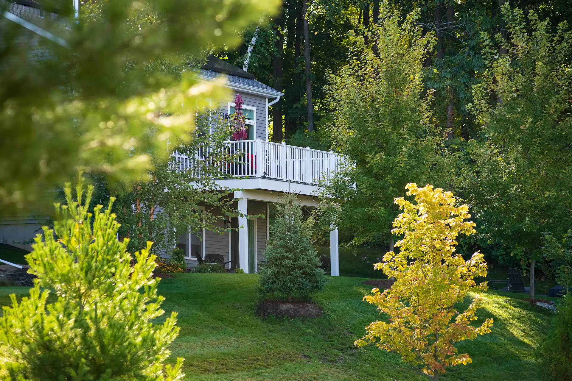 home rear with upper deck and landscaped yard through trees