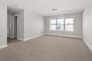 large empty carpeted bedroom with wide picture window