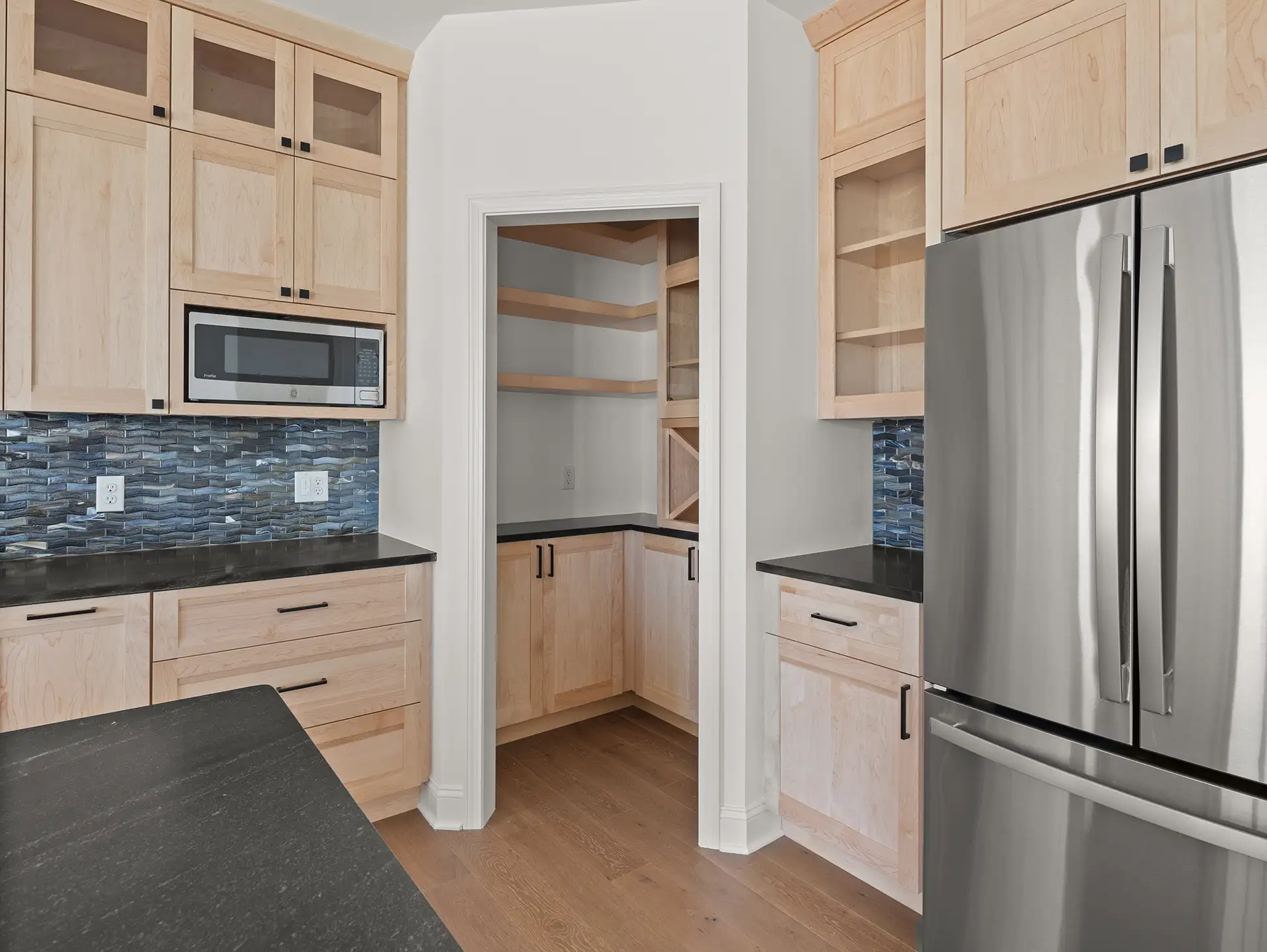 light wood kitchen blue glass backsplash arched pantry door