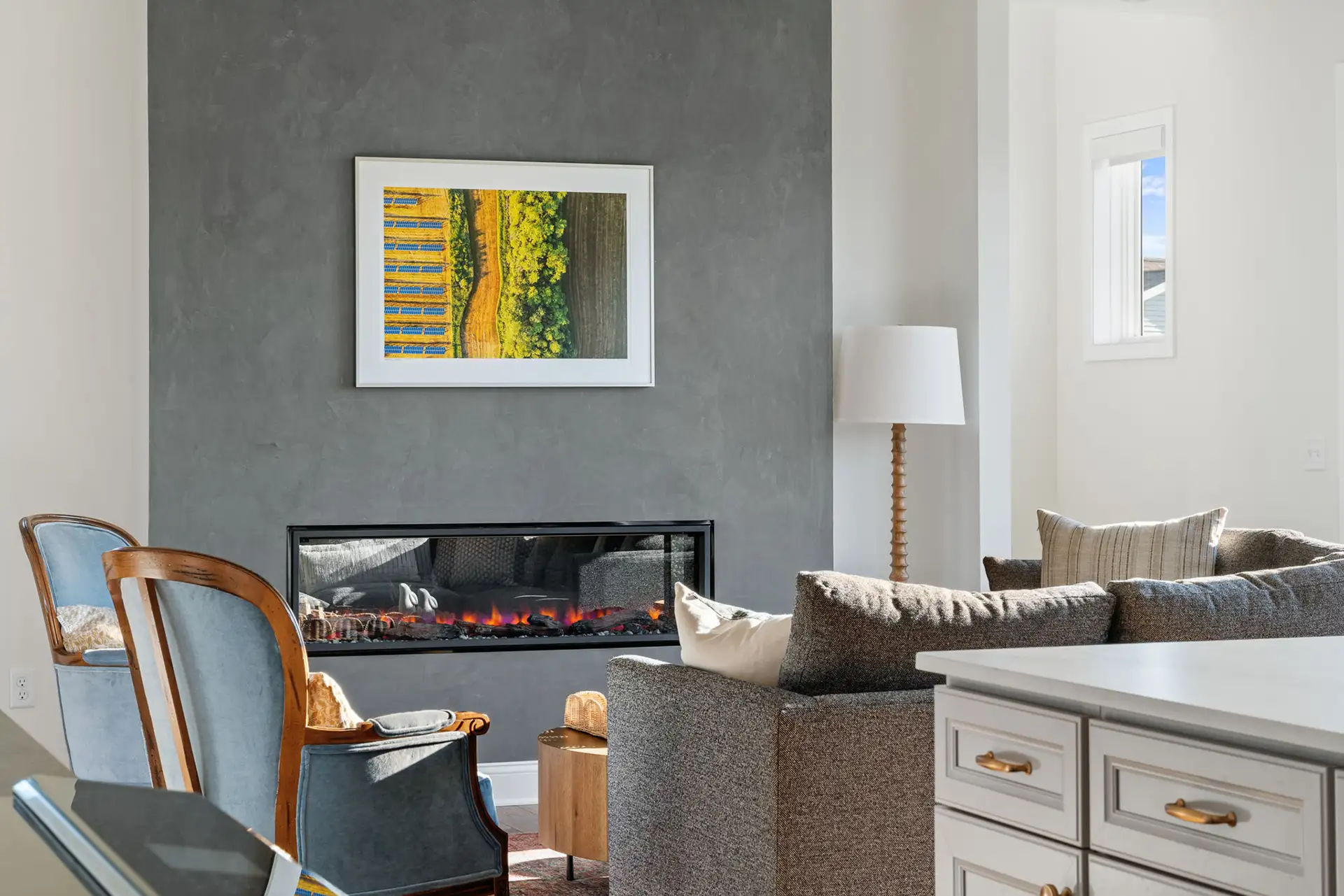 living room with lit linear fireplace and blue accent chair