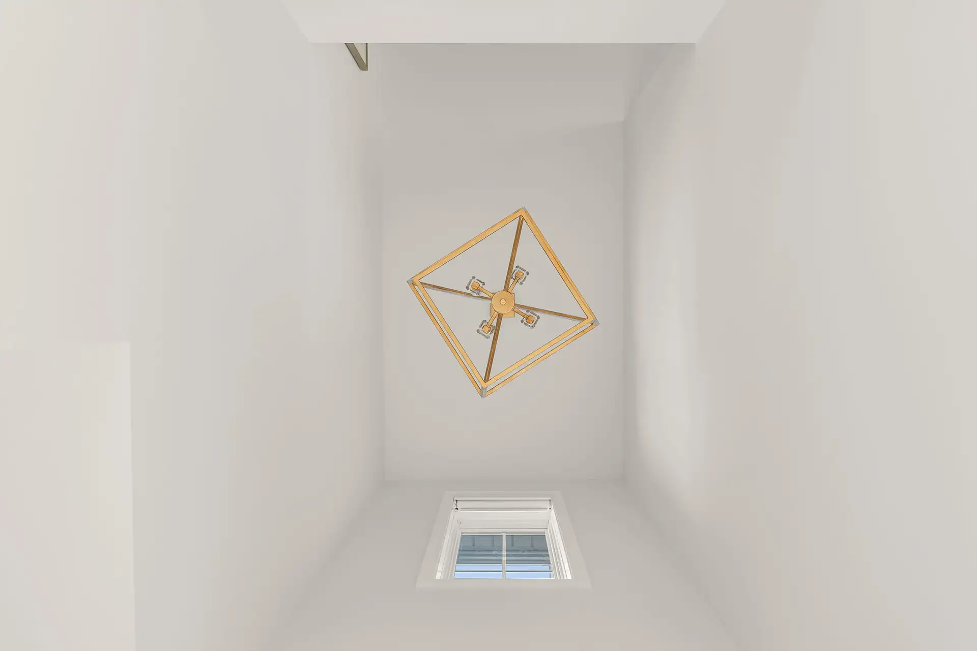 looking up stairwell gold geometric chandelier skylight