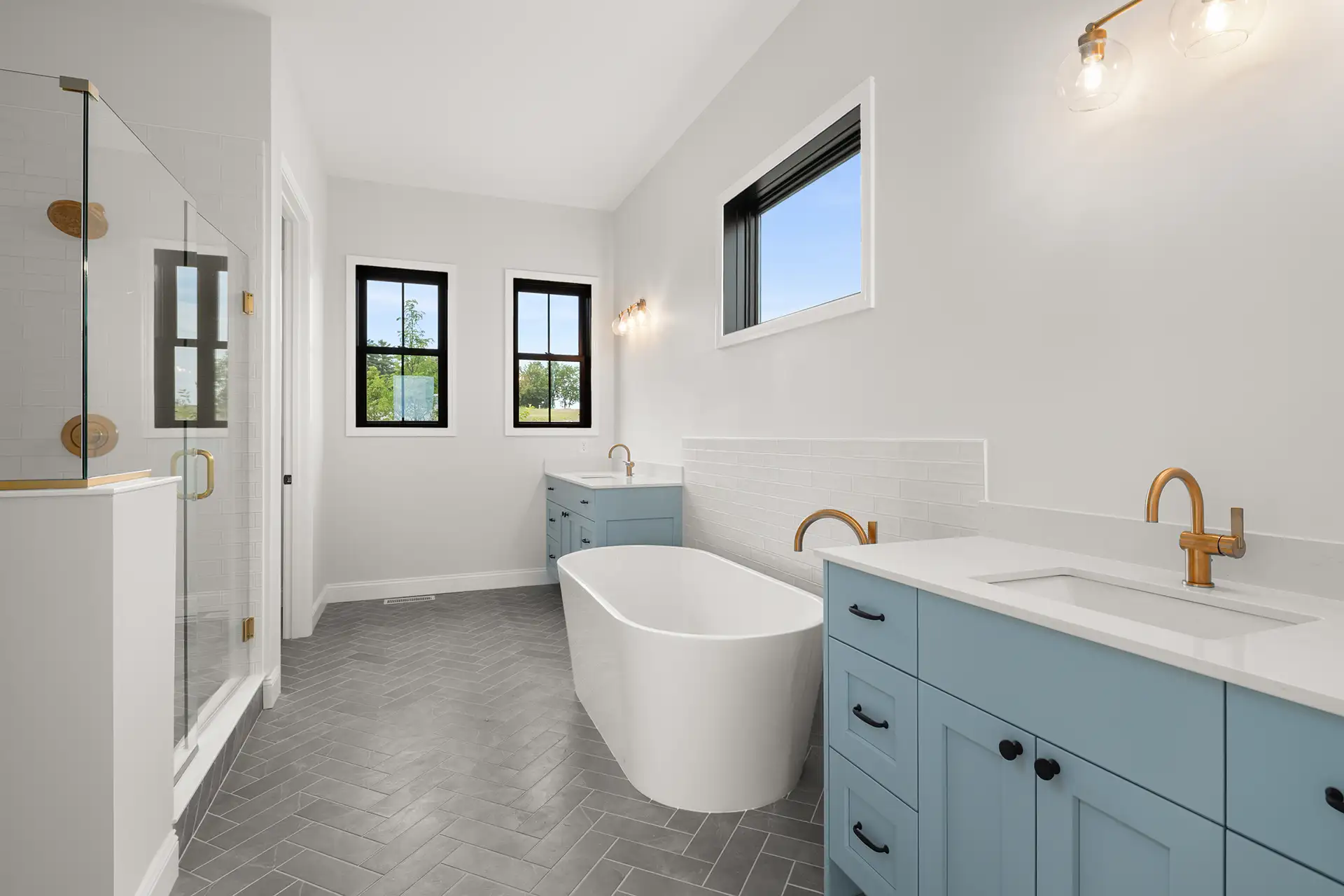 master bathroom with freestanding tub blue cabinets and gold fixtures