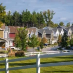 neighborhood street view with white fence and pine tree backdrop
