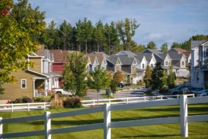 neighborhood street view with white fence and pine tree backdrop