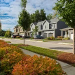 neighborhood street with garage homes and colorful autumn shrubs